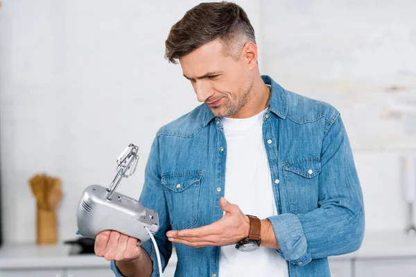 Verwirrter Erwachsener Mann Hält Mixer Der Hand Und Schaut Ihn — Stockfoto