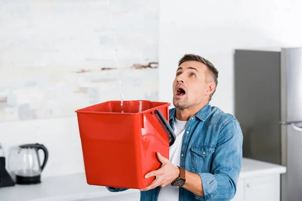 Scared Man Holding Plastic Bucket Looking Ceiling Kitchen — Stock Photo, Image