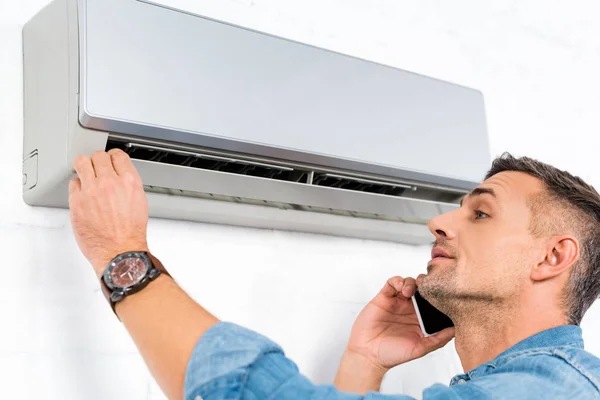 Knappe Man Praten Smartphone Tijdens Het Controleren Van Airconditioner — Stockfoto