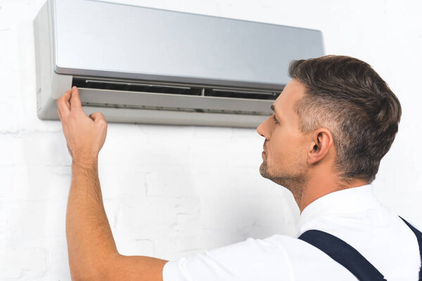 handsome repairman fixing air conditioner 