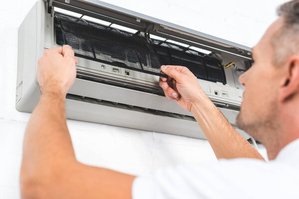 close up view of man fixing filter of air conditioner 