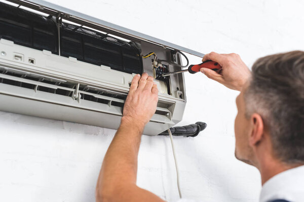 close up view of adult repairman repairing air conditioner 
