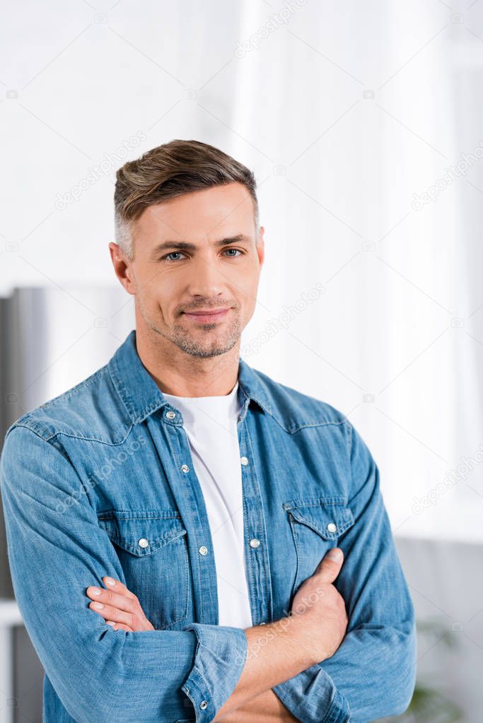 handsome man with crossed arms smiling at camera 