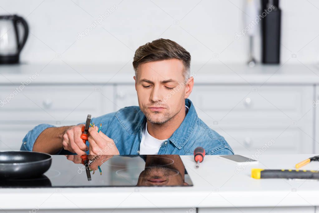 handsome man repairing electric stove at kitchen 