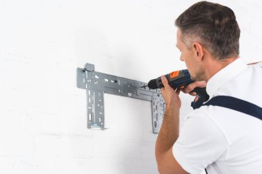 adult foreman installing bracket for air conditioner with drill clipart