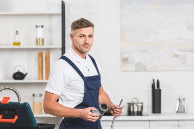 Yetişkin tamirci boruları tamir ve kameraya bakarak mutfak musluk için holding