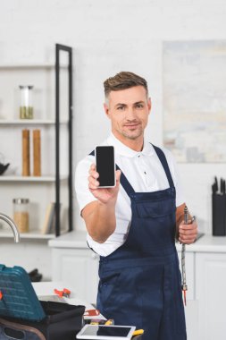 Boru ve smartphone boş ekran ile tutarak gülümseyen yetişkin ev erkeği
