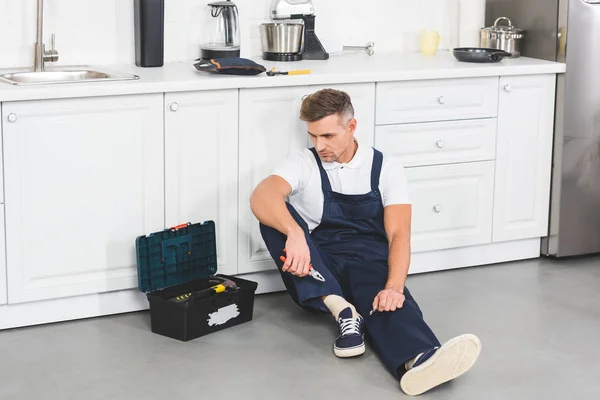 Upset Adult Repairman Sitting Holding Pliers Kitchen — Stock Photo, Image