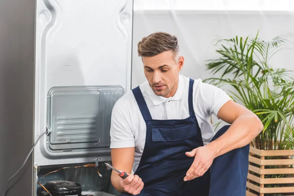 Verwirrter Erwachsener Reparateur Schaut Beim Reparieren Von Kühlschrank Auf Schraubenzieher — Stockfoto