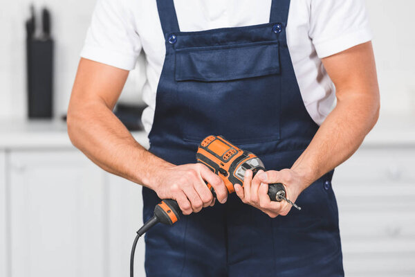 cropped view of repairman holding drill inhands 