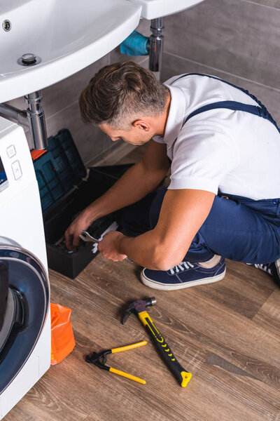 adult repairman sitting on floor and taking repair tools from box