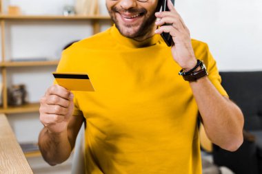 smartphone üzerinde konuşmak ve kredi kartı tutan adamın kırpılmış görünümü