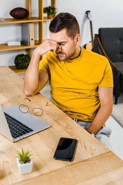Homem Cansado Sentado Perto Laptop Smartphone Casa — Fotografia de Stock Grátis