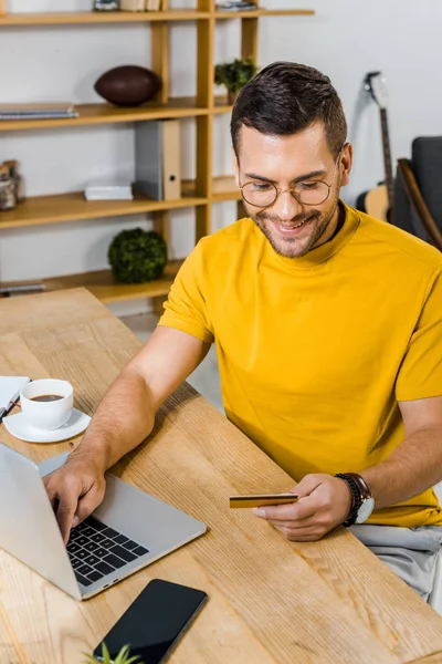 Hombre Guapo Mirando Tarjeta Crédito Mientras Utiliza Ordenador Portátil —  Fotos de Stock