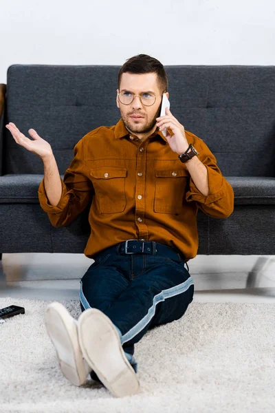 Dissatisfied Man Sitting Carpet Talking Smartphone — Stock Photo, Image