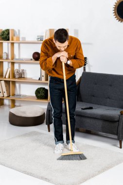üzgün adam süpürge ile modern oturma odasında ayakta 