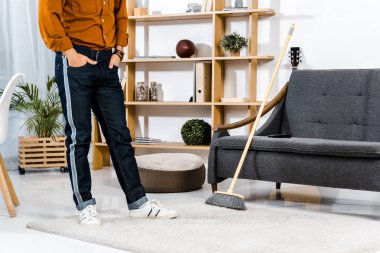 adam süpürge modern oturma odasında ayakta kırpılmış görünümünü 