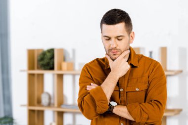 upset man doing thinking gesture in modern living room  clipart