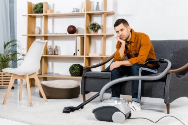 modern oturma odası kanepe hoover ve kameraya bakarak yakın oturan adam üzgün