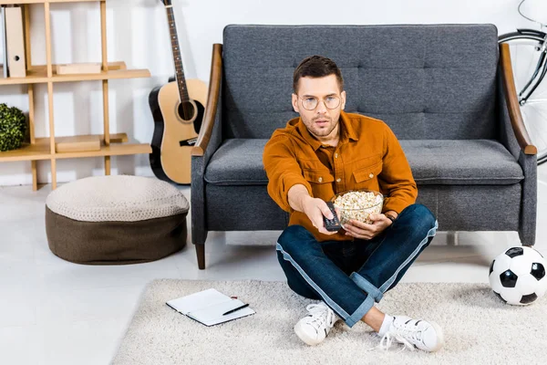 Surprised Man Sitting Carpet Popcorn Bowl Holding Remote Control Living — Stock Photo, Image