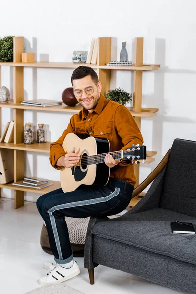 Hombre Alegre Gafas Tocando Guitarra Acústica Mientras Está Sentado Sofá — Foto de Stock