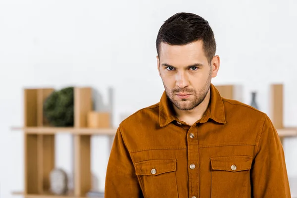 Aufgebrachter Mann Steht Modernen Wohnzimmer Und Blickt Kamera — Stockfoto