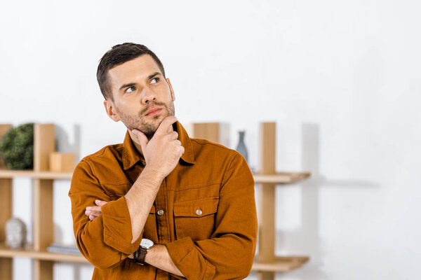 handsome man standing in modern living room doing thinking gesture