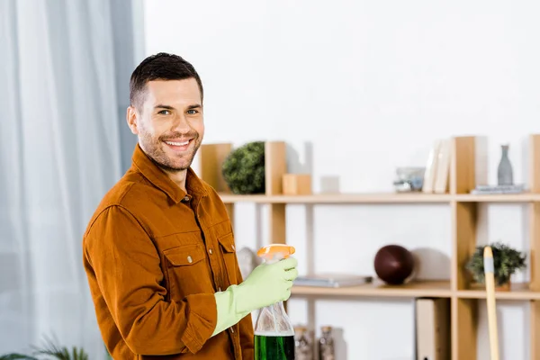 Hombre Guapo Pie Sala Estar Moderna Sosteniendo Botella Mientras Sonríe — Foto de Stock