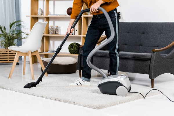 cropped view of man in modern living room cleaning house with hoover 