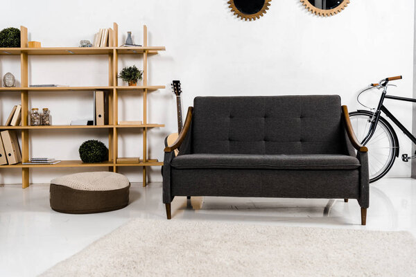 современная гостиная с диваном, акустической гитарой, полками и растениями
