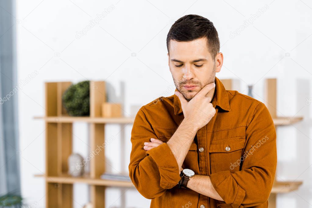 upset man doing thinking gesture in modern living room 