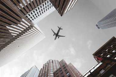 bottom view of skyscrapers and airplane in cloudy sky in new york city, usa clipart