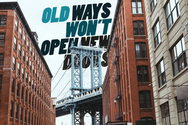 urban scene with buildings, brooklyn bridge and "old ways wont open new doors" lettering in new york city, usa