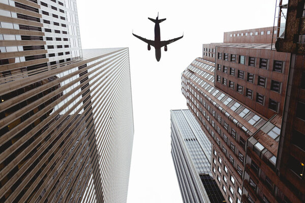Bottom view of skyscrapers and clear sky with airplane in new york city, usa