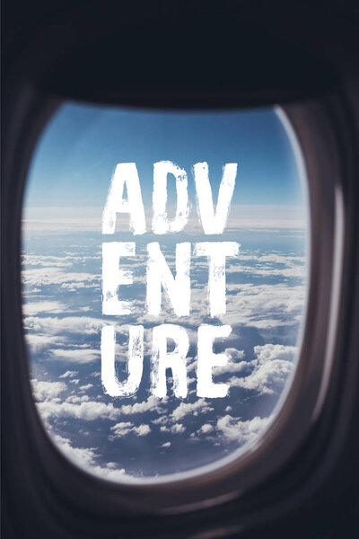 вид голубого облачного неба с самолета с надписью "приключение" на окне
