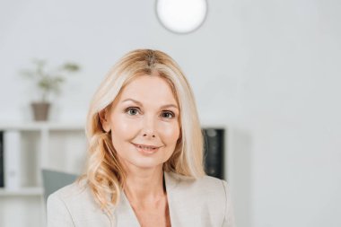 office kamerada gülümseyen güzel sarışın olgun iş kadını portresi