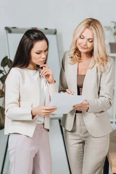 Smiling Mature Businesswoman Pointing Papers Discussing Work Young Female Colleague — Stock Photo, Image