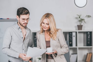 fincan kahve ve office gazetelerde bakarak gözlük genç işadamı ile gülümseyen iş kadını