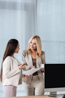güzel iş kadınları ayakta gülümseyen ve office birlikte gazetelerde tartışmaya
