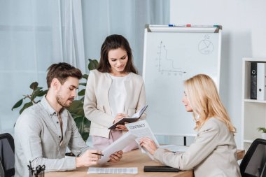 Genç işkadını defter ve belgeleri Office ile çalışma arkadaşları yazılı gülümseyen