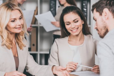 Genç iş adamları ve oturan ve birlikte çalışan ofiste Olgun kadın akıl hocası gülümseyen