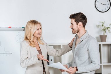 genç işadamı ve olgun işkadını birbirlerine ofiste gülümseyen