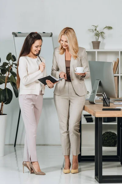 Mooie Gelukkig Zakenvrouwen Met Kopje Koffie Notebook Permanent Samen Bespreken — Stockfoto