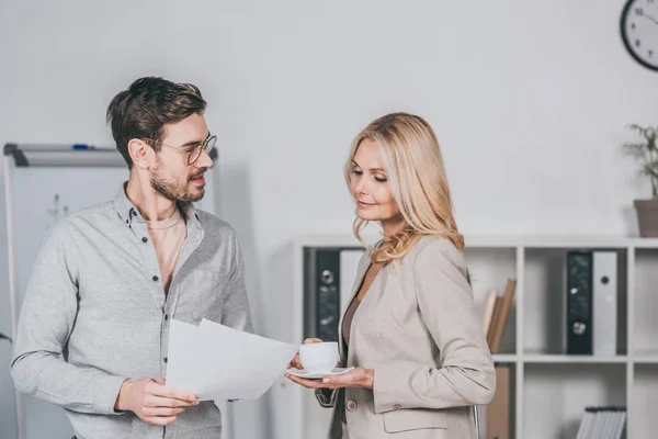 Smiling Young Businessman Eyeglasses Holding Papers Looking Buisnesswoman Cup Coffee — Stock Photo, Image