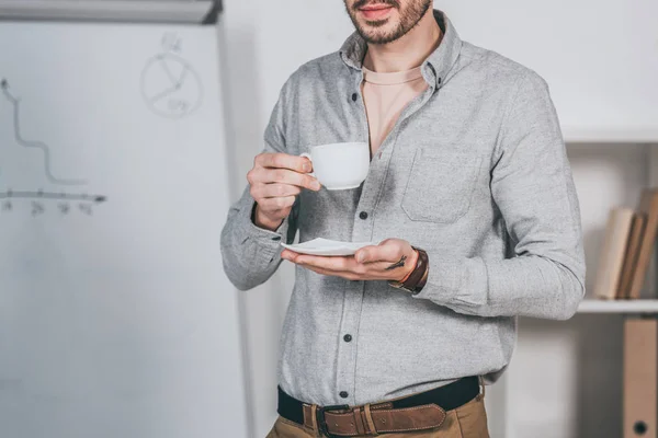 Recortado Disparo Barbudo Joven Empresario Sosteniendo Taza Café Platillo Oficina —  Fotos de Stock