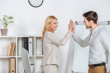 happy young businessman giving high five to mature mentor in office  clipart