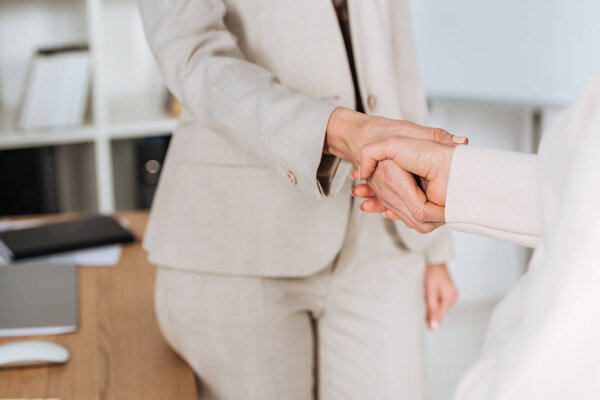 close-up partial view of professional businesswomen shaking hands in office