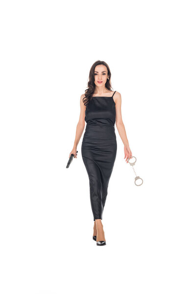 elegant female secret agent in black dress holding gun and handcuffs, isolated on white