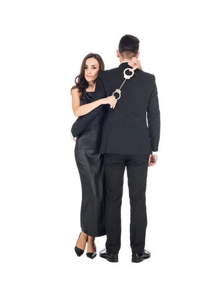 Mulher Elegante Vestido Preto Abraçando Homem Segurando Algemas Isolado Branco — Fotografia de Stock