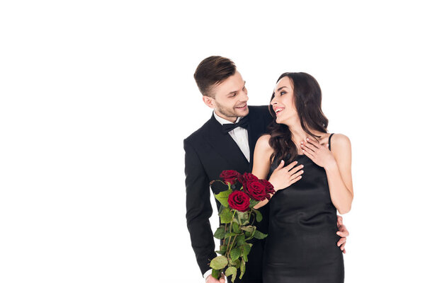happy couple in black clothes posing with red roses on valentines day, isolated on white